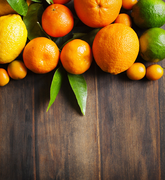 Fresh citrus fruits with leaves on wooden background - Photo, image