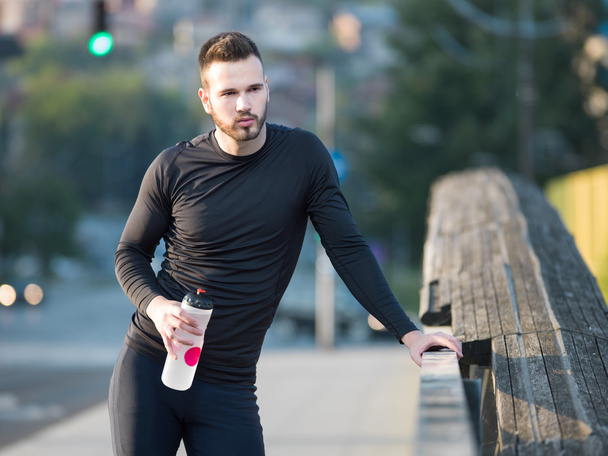 Young man jogging with plastic bottle - Valokuva, kuva