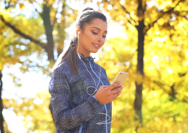 woman holding phone in autumn park - Foto, imagen