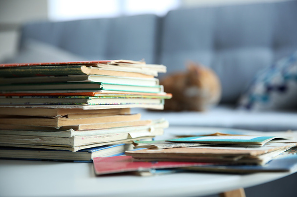 Pile of old books on white table in the room. Focus on books and blurred background - Foto, immagini