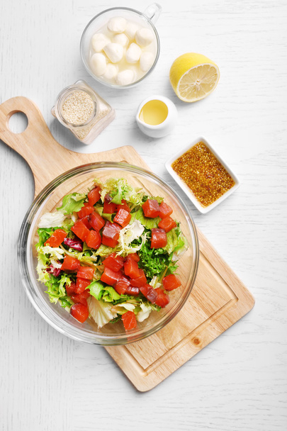 Tasty salad in glass dish on color wooden table background - 写真・画像