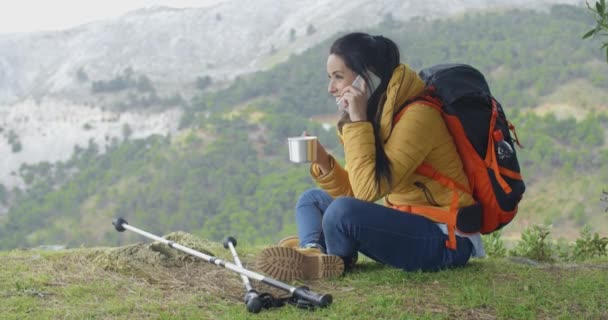 woman drinking and talking on phone in mountains - Video