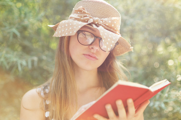 schöne Landmädchen liest ein Buch in der Natur, genießt sonnige  - Foto, Bild
