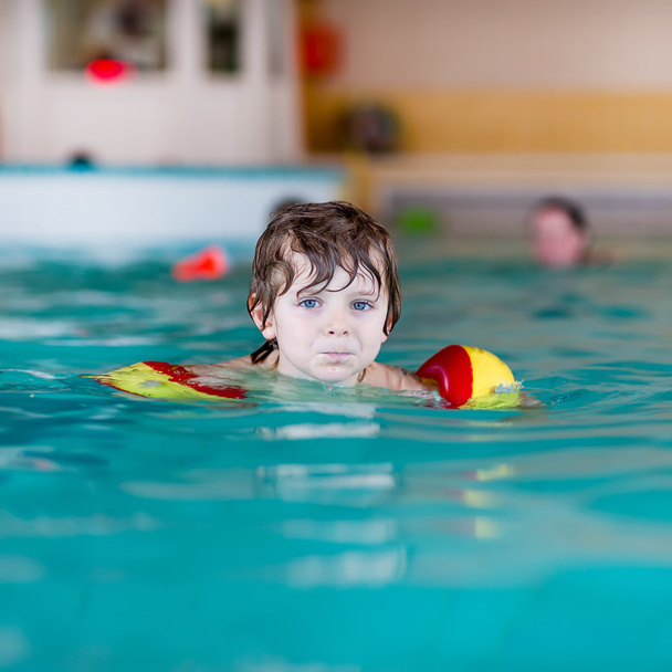 pieni poika, jolla on uimareita opettelemassa uimaan uima-altaassa
 - Valokuva, kuva