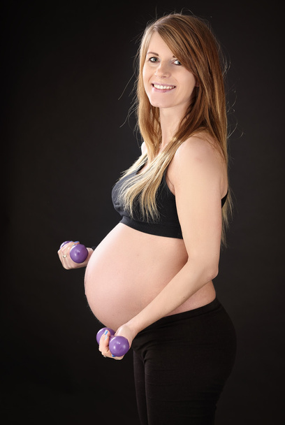 Beautiful pregnant woman exercising with dumbbells - 写真・画像