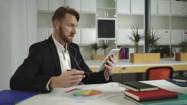 Empresario mira gráficos y habla con una tableta
 - Imágenes, Vídeo