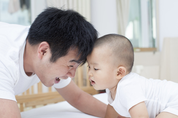 Igazi kínai apa és fia játszik az ágyban - Fotó, kép