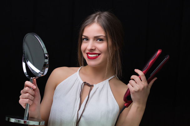 Mujer con espejo y plancha de pelo plano
 - Foto, imagen