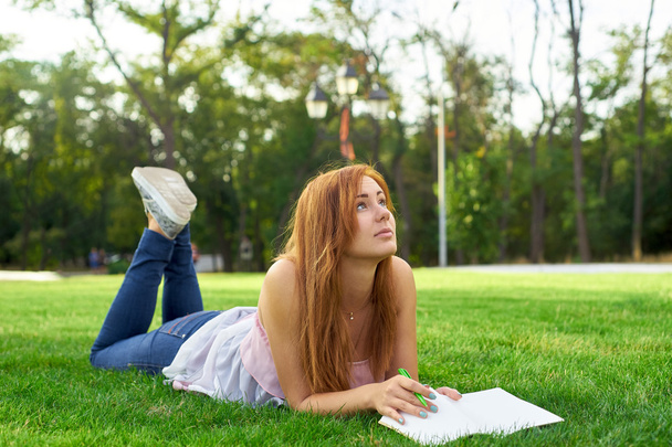 woman lying on a lawn with a diary - 写真・画像
