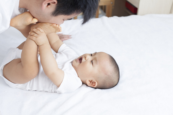 Chinese vader en zoon spelen in bed - Foto, afbeelding