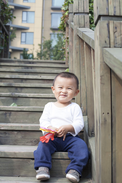 Iloinen kiinalainen vauva poika pelaa lelu portaissa
 - Valokuva, kuva