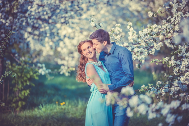 Young beautiful couple in love among apple trees - Фото, зображення