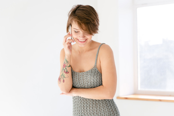 Charming cheerful woman talking on cell phone near the window - Photo, Image
