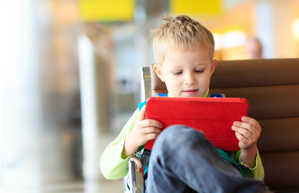 rapazinho olhando para touch pad no aeroporto
 - Foto, Imagem