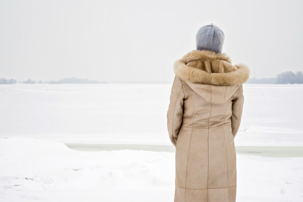 Nainen lähellä Jäätynyttä jokea talvella
 - Valokuva, kuva