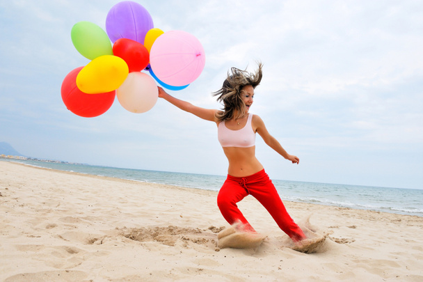 Mujer joven con globos de colores en la playa
 - Foto, imagen