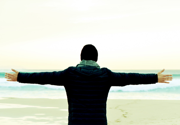 uomo in cappotto con le braccia in aria di fronte all'oceano
 - Foto, immagini