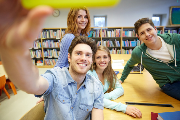 students with smartphone taking selfie in library - Photo, image