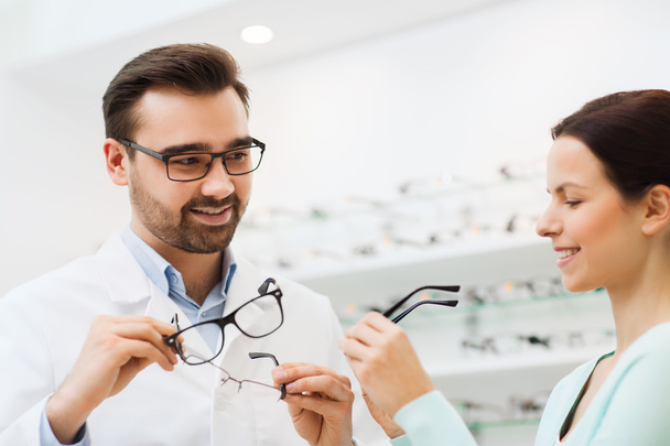 woman and optician showing glasses at optics store - Foto, Imagen