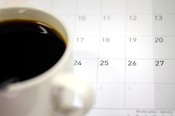 Taza de café colocada en el calendario
 - Foto, Imagen