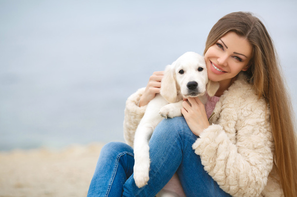 A young woman near the sea with a puppy Retriever - Foto, Imagen