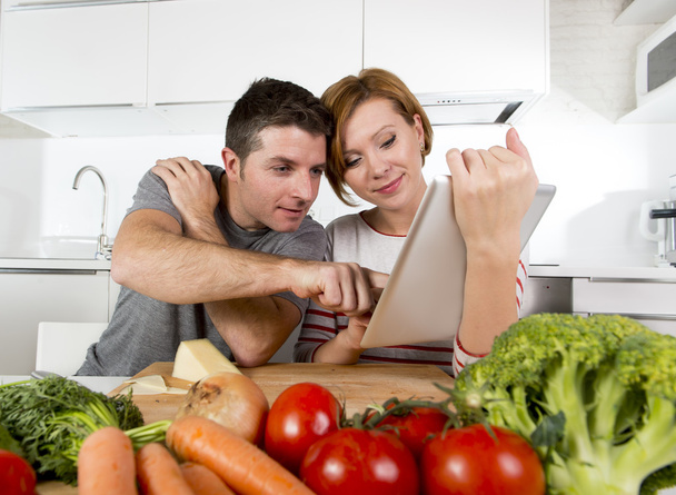 Coppia americana in cucina domestica moglie seguendo la ricetta in pad digitale lavorare insieme con il marito
  - Foto, immagini