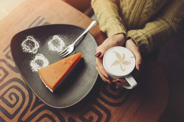 Menina encantadora beber cappuccino e comer cheesecake. Mãos c
 - Foto, Imagem