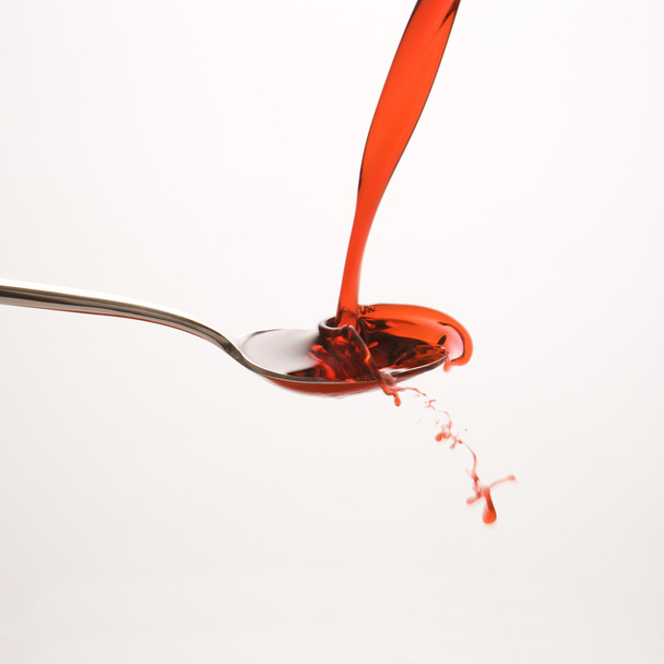 Spoon and red medicine. - Фото, изображение