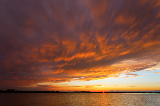 Rode zonsondergang boven de zee, rijk aan donkere wolken, lichtstralen - Foto, afbeelding