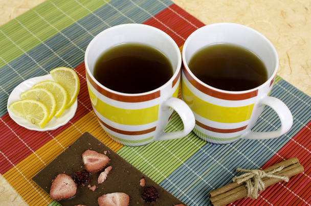 Dos tazas de té, chocolate, limón y canela
. - Foto, Imagen