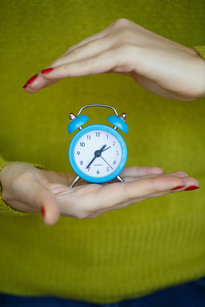 Pieni sininen herätyskello naisten käsissä
 - Valokuva, kuva