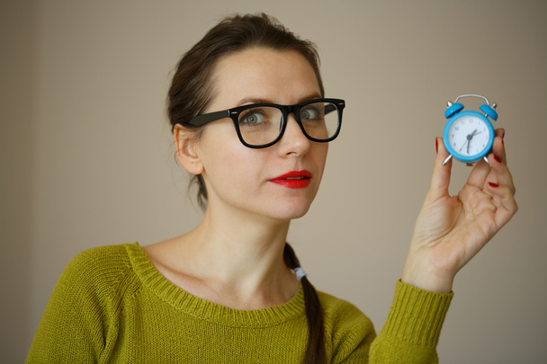 Маленький синій будильник в руках емоційної молодої жінки
 - Фото, зображення