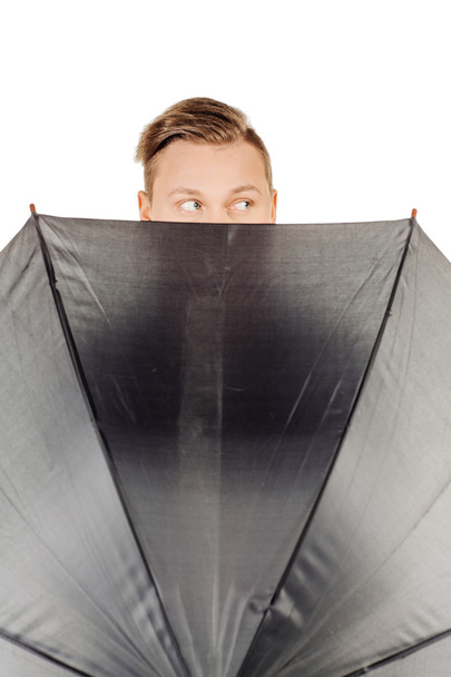 young man hidden in umbrella against white background - Photo, image