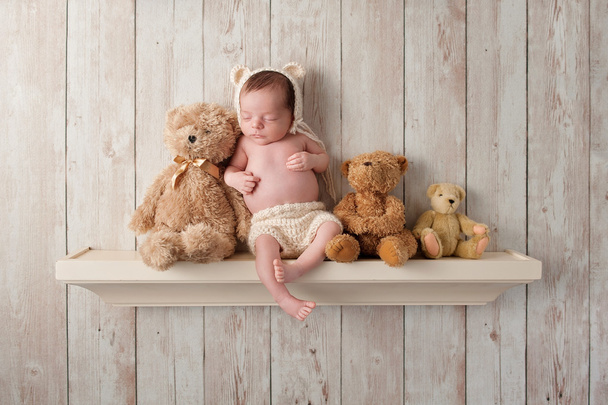 Nouveau-né garçon sur une étagère avec ours en peluche
 - Photo, image
