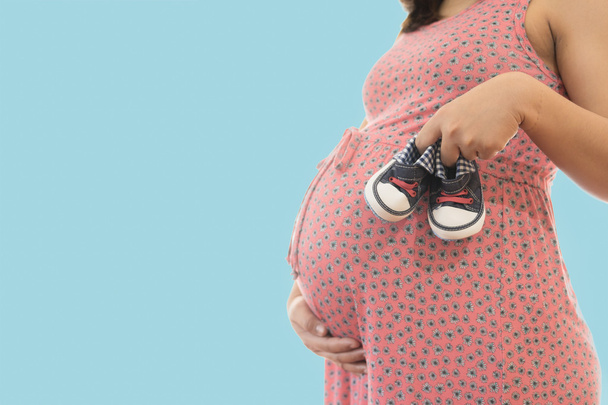 kleine Schuhe für das ungeborene Baby im Bauch der Schwangeren o - Foto, Bild