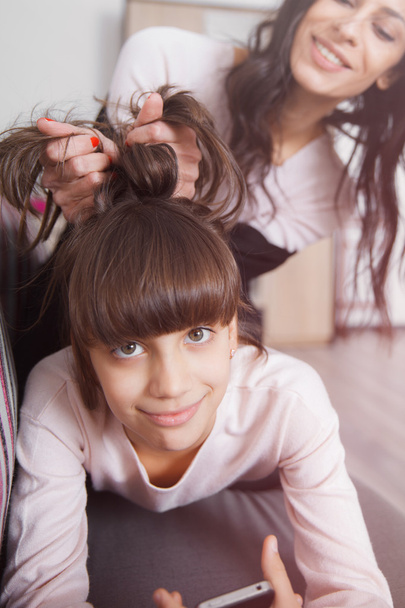 glückliche junge Mutter spielt mit den Haaren ihrer Tochter - Foto, Bild