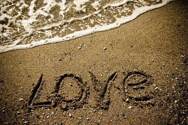 The inscription "LOVE" on a wet sand seacoast. Toned - 写真・画像