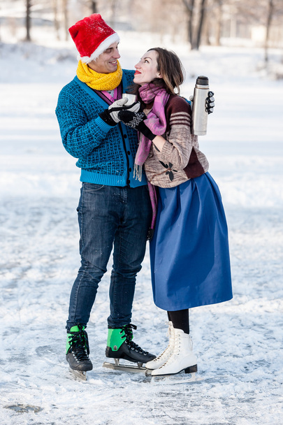 Happy couple having fun and drinking hot tea on rink outdoors. - Photo, Image