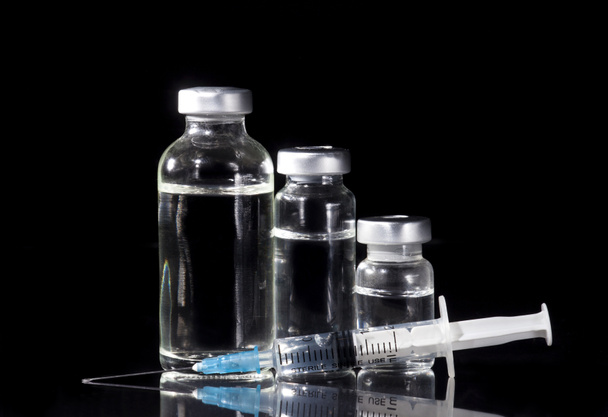 Glas Medizin Ampullen und Spritze auf schwarzem Hintergrund - Foto, Bild