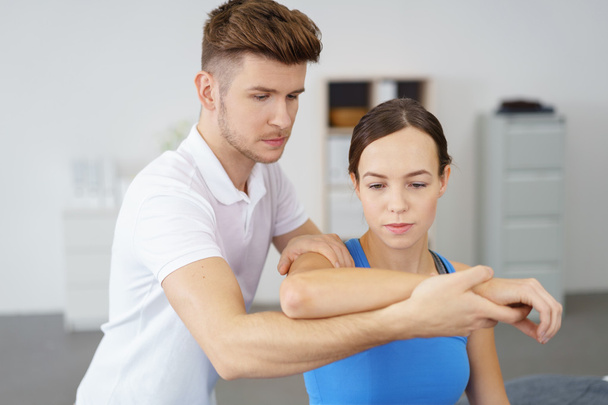 Young Professional Male Physical Therapist Examining the Arm of a Female Patient - Zdjęcie, obraz