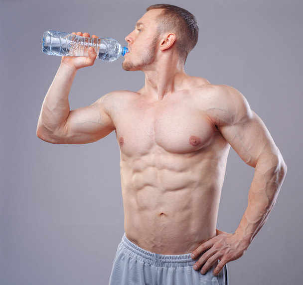 Athlete man drinking water over dark background - Zdjęcie, obraz