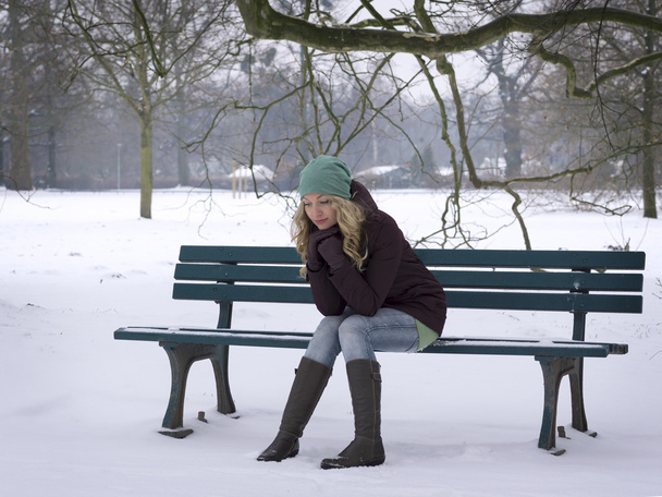 vrouw alleen zitten op een bankje in de winter - Foto, afbeelding