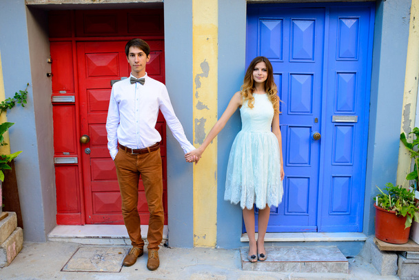 young couple standing next to a bright blue door - Фото, изображение