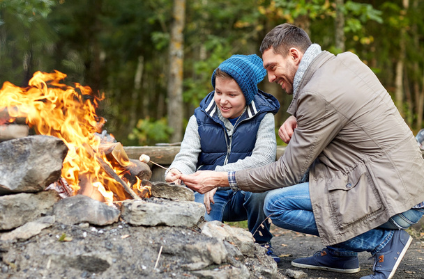 father and son roasting marshmallow over campfire - Фото, зображення