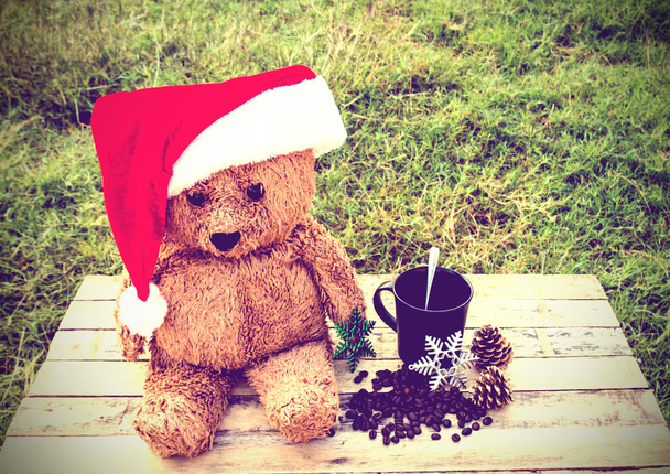 Teddy bear wearing santa claus hats and coffee cup on a wooden t - Photo, Image
