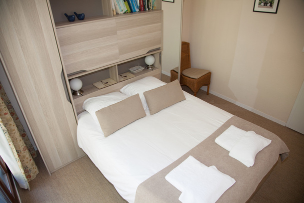 Doppelbett im Schlafzimmer mit Schreibtischlampe in der Nähe - Foto, Bild