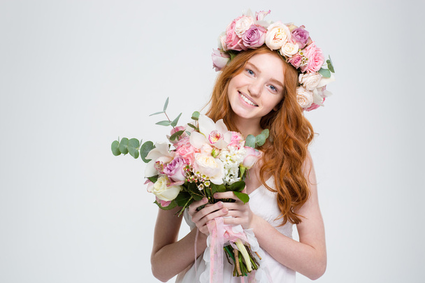 Sonriente joven atractiva en guirnalda sosteniendo ramo de flores
 - Foto, imagen