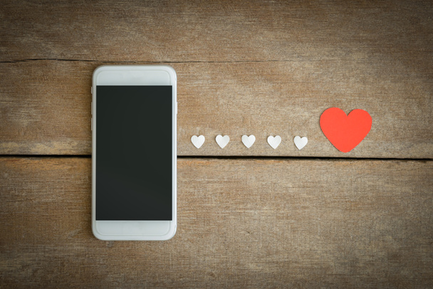 Smartphone y corazones de papel sobre fondo de madera
 - Foto, Imagen