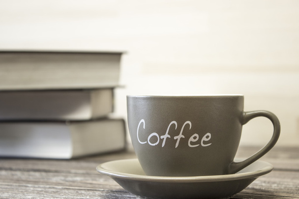 Egy csésze kávét a háttérben a verem a könyvek. A hangsúly a szélén a kupa - Fotó, kép