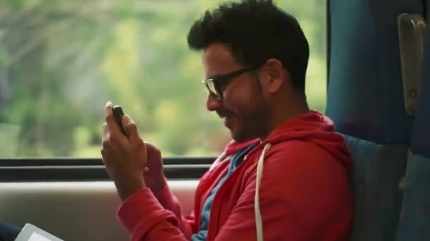 Man met behulp van zijn mobiel en glimlachen van binnenkant van bewegende trein - Video